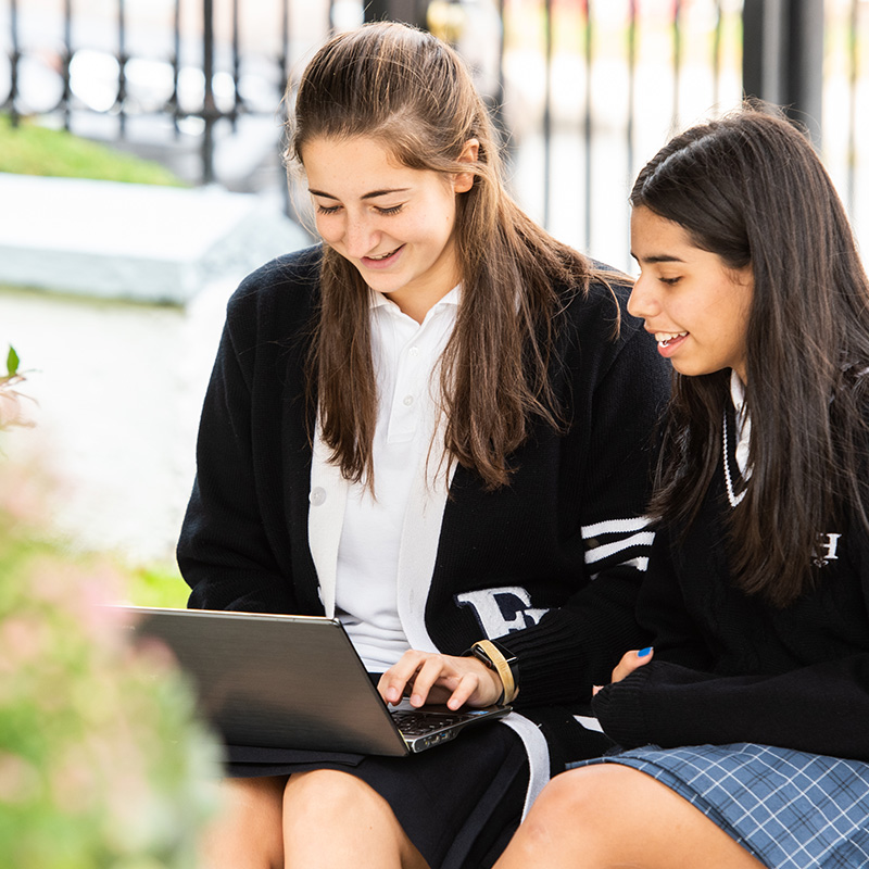 Two students in outdoor courtyard with laptop